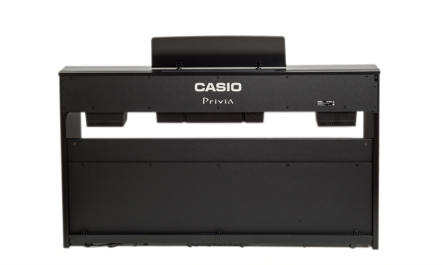 Casio PX-870 сзади на белом фоне: тыльная сторона корпуса с логотипом Casio Privia, решётки динамиков по краям клавиатурного блока и открытый низ тумбы