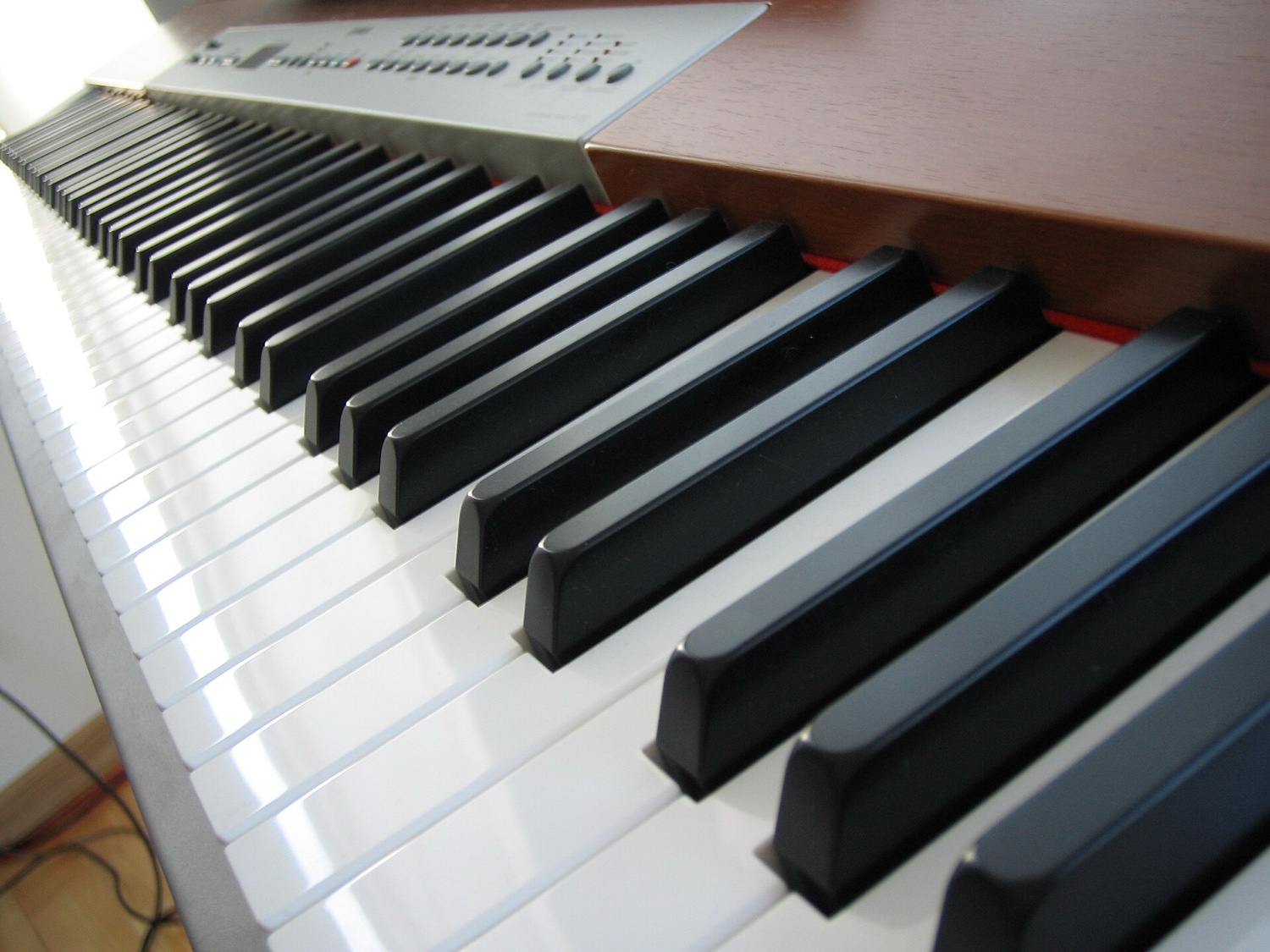 Клавиатура цифрового пианино Yamaha P120 с уровня клавиш: белые и чёрные клавиши уходят вдаль, сверху — узкая панель управления с кнопками