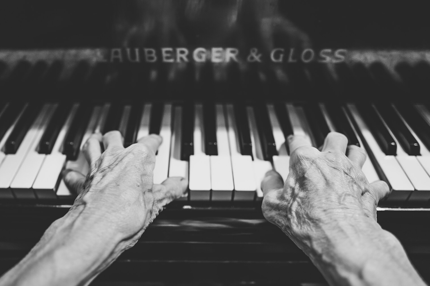 Чёрно-белый снимок: две руки пианиста на клавиатуре пианино Lauberger & Gloss, пальцы на белых и чёрных клавишах