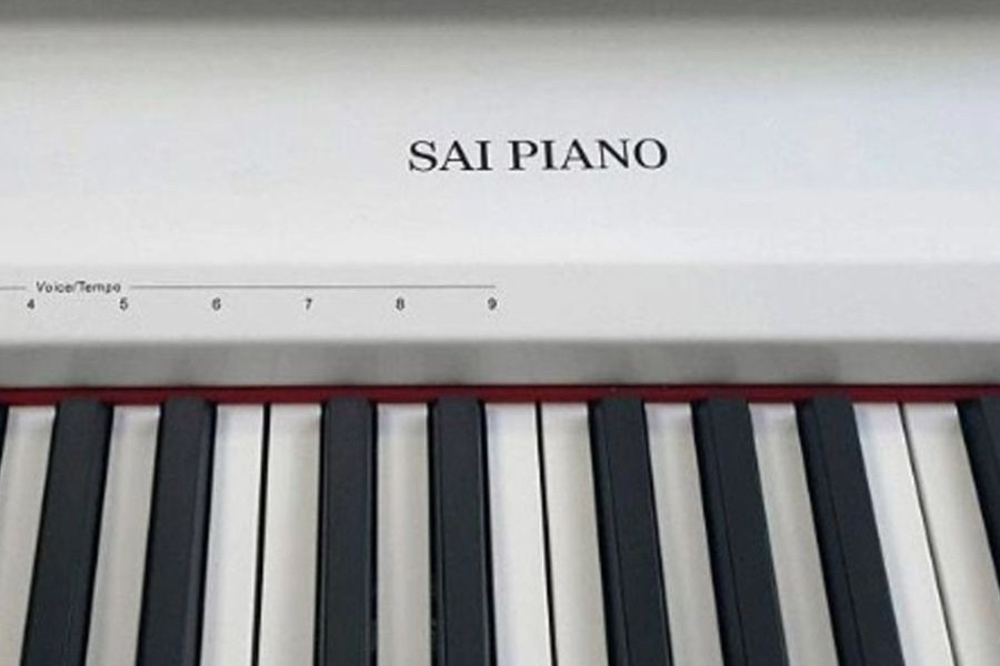 Крупный план белого Sai Piano P-9: надпись SAI PIANO на панели, шкала Voice/Tempo с цифрами 4–9, под ней красный войлок и открытые клавиши