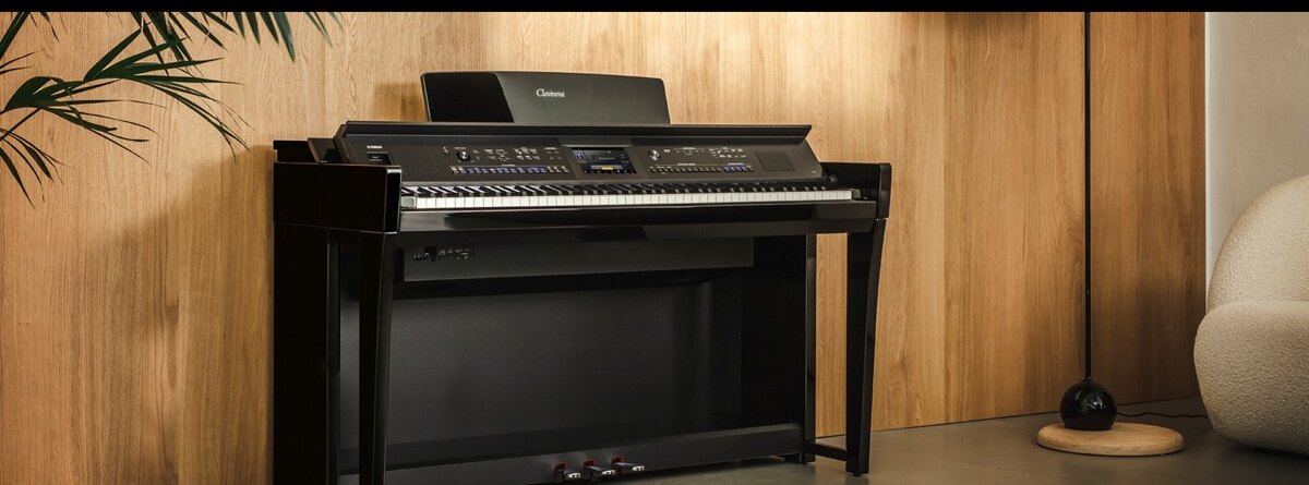 Цифровое пианино Yamaha Clavinova CVP-905 в чёрном полированном корпусе у деревянной стены, на панели над клавишами небольшой цветной экран между двумя рядами кнопок