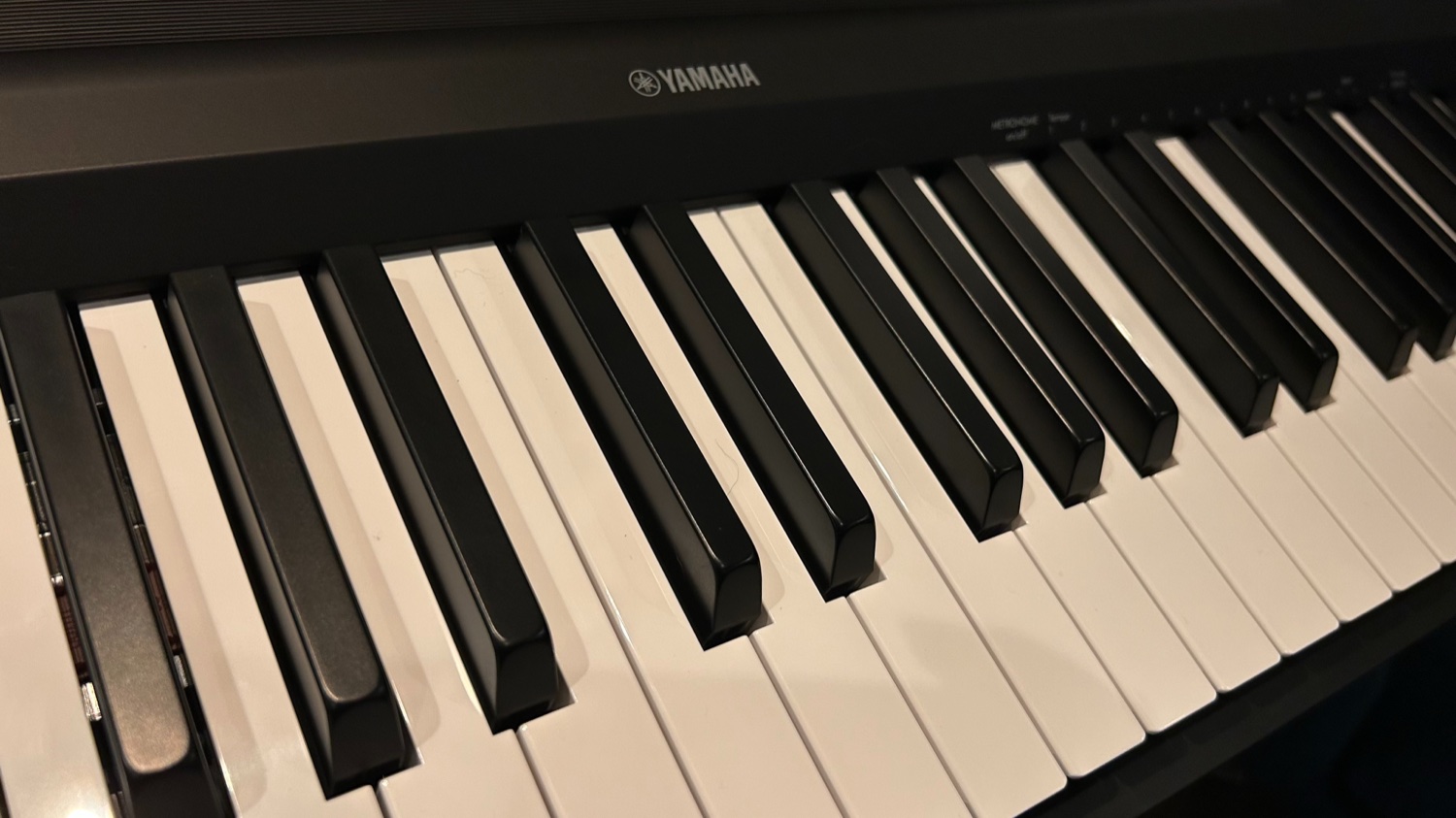 Крупный план матовых чёрных и белых клавиш Yamaha P-145 с логотипом YAMAHA на корпусе