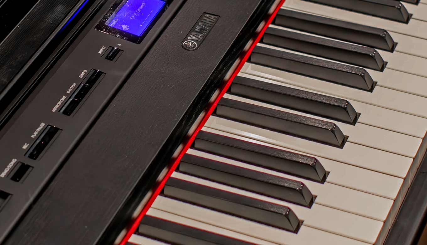 Клавиши цифрового пианино Yamaha P-525 крупным планом сбоку: матовые кремовые белые клавиши и чёрные клавиши с продольной шероховатой фактурой